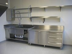 an empty kitchen with stainless steel cabinets and drawers on the wall, in front of a staircase