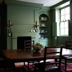 a dining room with green walls and wooden table in front of a fire place oven