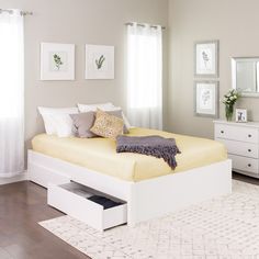 a white bed sitting in a bedroom on top of a hard wood floor next to a window