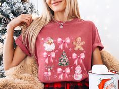 Spread some holiday cheer with this adorable pink Christmas T-shirt. Featuring a charming watercolor design of Santa Claus, bows, a gingerbread man, a Christmas tree, a reindeer, and a snowman, this shirt is perfect for the festive season. This shirt is stylish and cozy and made from soft and comfortable Comfort Colors 1717 fabric. Pink Christmas design Watercolor style Comfort Colors 1717 fabric Soft and comfortable Perfect for the holidays Are you looking for a unique Christmas t-shirt? Look n Cute Pink Christmas Tops, Cute Pink Holiday Tops, Cute Pink Holiday Top, Cute Pink Top For Holiday, Cute Pink Christmas T-shirt, Pink Coquette Christmas, Coquette Shirt, Coquette Christmas, Christmas Pink