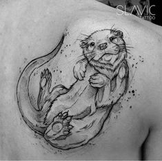 an otter tattoo on the back of a man's shoulder