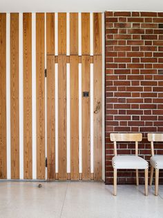 two chairs sitting next to each other in front of a brick wall and wooden door