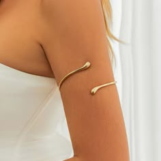 Unveiling Delicate Charm: The Minimalist Dewdrop Boho Arm Bracelet - A Symphony of Effortless Style Embrace the captivating allure of understated elegance with the Minimalist Dewdrop Boho Arm Bracelet, a captivating piece that blends contemporary design with a touch of bohemian flair. This enchanting bracelet features a single, polished metal water drop delicately suspended on an open upper arm cuff. The result is a look that's both undeniably elegant and effortlessly cool. A Symphony of Effortl Sun Goddess Costume, Arm Jewellery, Arm Cuff Jewelry, Gold Arm Cuff, Upper Arm Cuff, Bracelet Arm, Upper Arm Cuffs, Arm Bracelet, Dope Jewelry Accessories