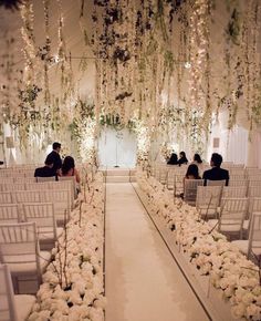 the aisle is decorated with white flowers and greenery