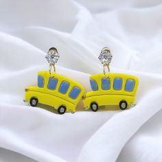 a pair of yellow and blue bus shaped earrings on white fabric with crystal eyeshades