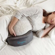 a pregnant woman laying on top of a pillow