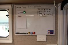 a white board with magnets on it next to a window