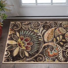 a door mat with an ornate design on the floor next to a potted plant