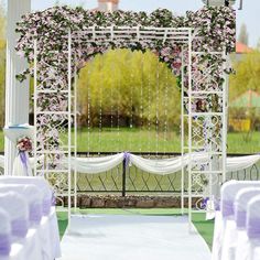 an outdoor wedding setup with white chairs and purple sashes