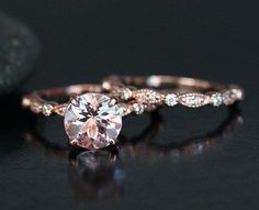 an engagement ring with a pink diamond in the center on a black surface next to a rock