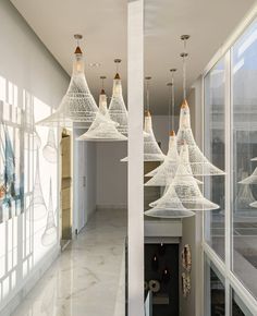 a room filled with lots of white lights hanging from the ceiling next to large windows