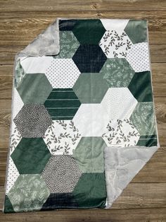 a green and white patchwork quilt on top of a wooden floor