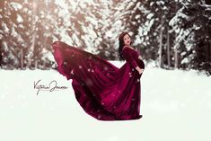 a woman in a purple dress is flying through the air with snow falling around her