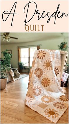 a white quilt sitting on top of a wooden floor next to a potted plant