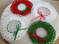 three crocheted christmas wreaths sitting on top of a doily covered plate