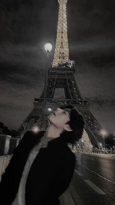 a man standing in front of the eiffel tower at night with his eyes closed