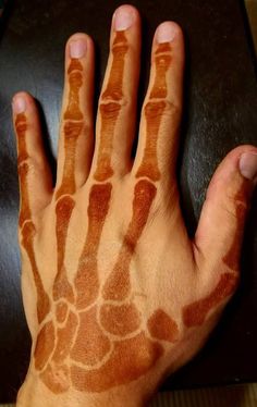 a person's hand painted with brown and white designs on it, next to a black table