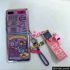 two cell phones are next to each other with keychains on the front and back