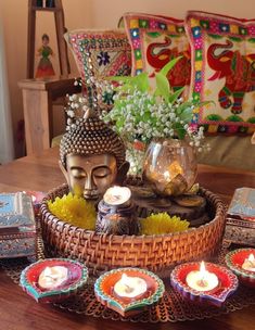 there is a basket with candles and buddha statues in it on top of the table