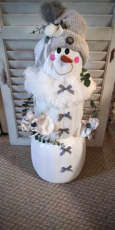 a snowman is sitting on top of a white vase