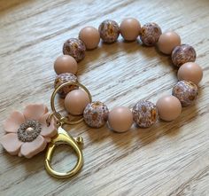 a close up of a bracelet on a table with a flower charm attached to it