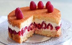 a cake with raspberries on top is cut in half and served on a plate