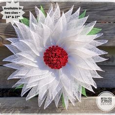 a white flower with red center sitting on top of a wooden table next to a fence