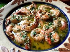 a blue and white plate with some shrimp in it on a floral design table cloth