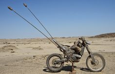 a dirt bike sitting on top of a metal stand in the middle of a desert