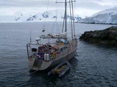 a boat with people on it in the water next to an ice covered mountain range