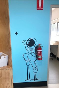 an image of a spaceman painted on the side of a door with a fire extinguisher next to it