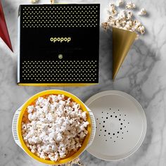 the popcorn box is next to two plates and a bowl with popcorn in it on a marble surface