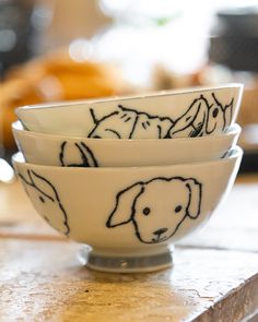 three bowls with dogs drawn on them sitting on a table