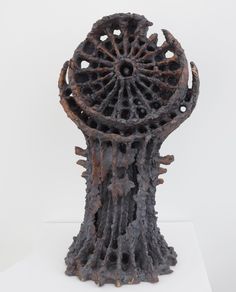 a sculpture made out of metal with holes in the center and an intricate design on top