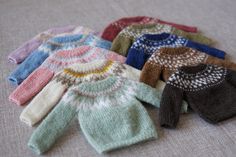 several knitted sweaters laid out on the floor, all different colors and patterns