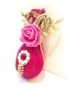 a pink purse with a rose and pearls on the handle is sitting next to a white wall