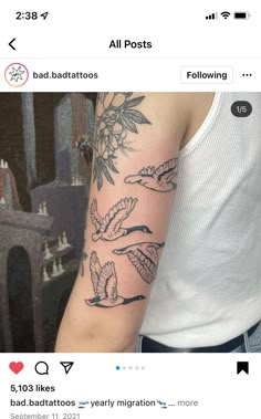 a person with a tattoo on their arm that has birds flying over it and flowers in the background