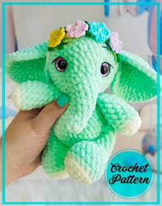 a crocheted elephant with flowers on its head is shown in front of a blue frame