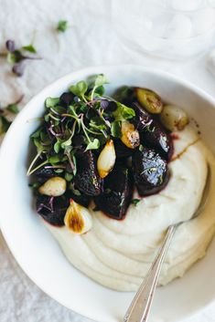 a white bowl filled with food on top of a table next to utensils