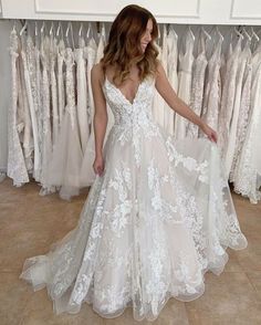 a woman standing in front of a rack of wedding dresses