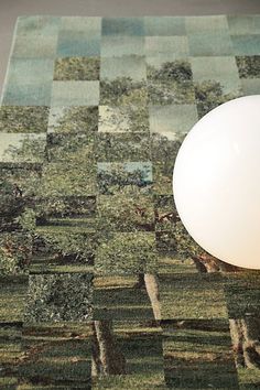 a white ball sitting on top of a green and blue rug next to a tree