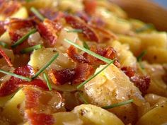 closeup of potatoes with bacon and herbs on them in a blue bowl, ready to be eaten