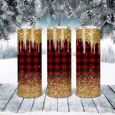 two red and black plaid pattern tumblers with straws in front of snow covered trees