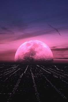 a large pink moon in the sky over a city