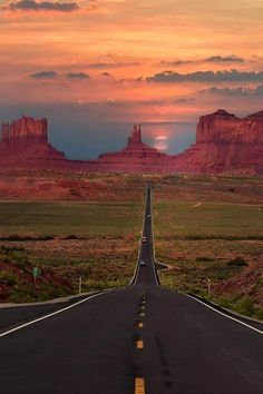 an empty road in the middle of nowhere with mountains in the background at sunset or sunrise