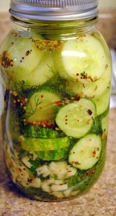 a mason jar filled with sliced cucumbers and spices