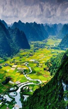 the valley is surrounded by mountains and green fields with small streams running through it, as seen from above