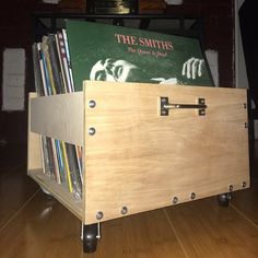 a wooden box on wheels with books in it sitting on top of a hard wood floor