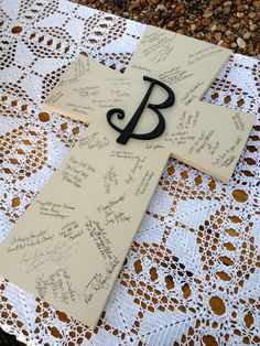 a cross with writing on it sitting on top of a doily covered tablecloth