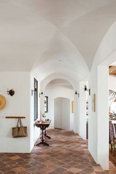 a long hallway with white walls and tile flooring next to a dining room table